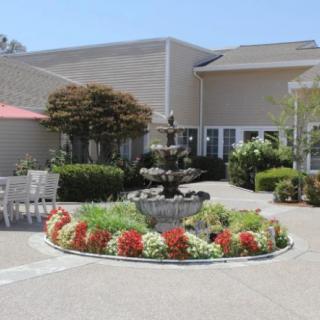 A peaceful courtyard featuring a central fountain surrounded by colorful flowers and greenery.