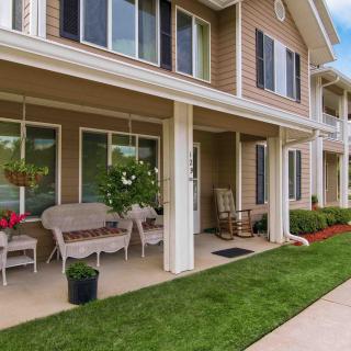 A cozy front porch with seating overlooking a well-manicured lawn.