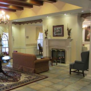 A cozy living room with a traditional design, featuring a chandelier, fireplace, and comfortable seating.
