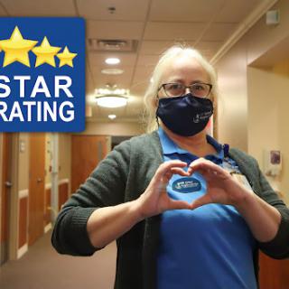 A dedicated healthcare worker proudly displays a heart shape, celebrating a five-star rating for their facility.