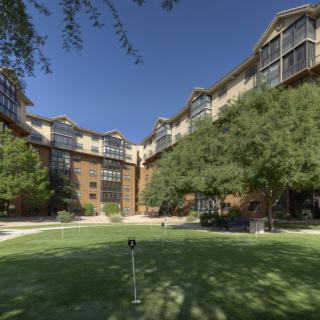 A large building with numerous windows, surrounded by trees and a well-maintained lawn.