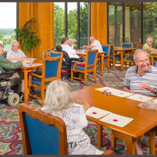 A group of seniors enjoying conversation in a community dining hall.