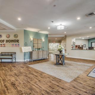 A welcoming lobby with wood flooring and modern decor, featuring a reception desk and seating area.