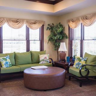 A cozy living room with green furniture and large windows.