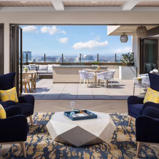 A modern living area opens up to a spacious outdoor terrace with a stunning city view.