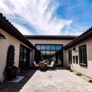 A modern courtyard with outdoor seating and architectural features under a blue sky.