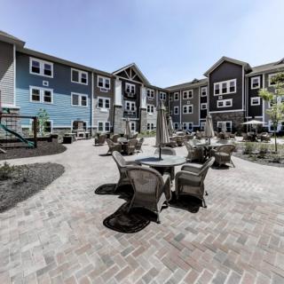 A modern apartment complex with a spacious courtyard featuring outdoor seating and well-maintained landscaping.