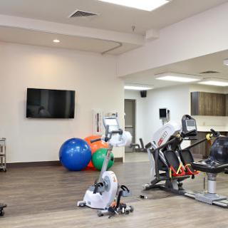 A modern fitness and rehabilitation gym featuring exercise equipment and colorful workout balls.