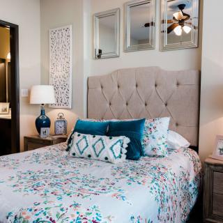A cozy bedroom featuring a bed with patterned bedding, decorative pillows, and a bedside lamp.