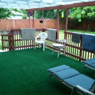 A cozy outdoor patio area with sunbathing chairs and towels hanging on the railing.
