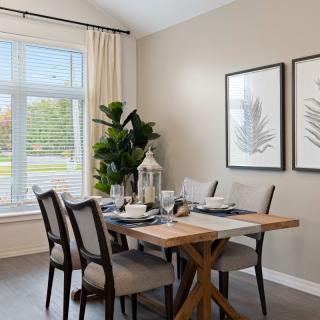 A well-appointed dining room with a wooden table, upholstered chairs, and natural light streaming through the window.