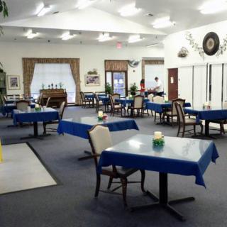 An empty dining room with tables covered in blue tablecloths.