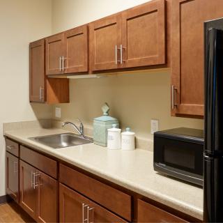 A kitchen with wooden cabinets, a microwave, and a countertop with a sink.