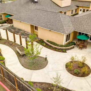 Aerial view of a landscaped garden with pathways and outdoor seating area adjacent to a building.