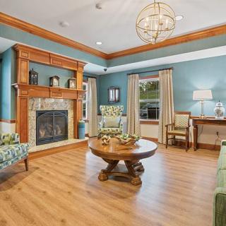 A cozy living room with a fireplace and stylish decor, featuring wood flooring, blue walls, and elegant furnishings.