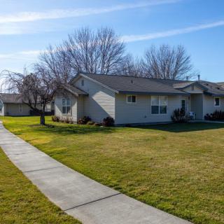 A suburban house with a well-maintained lawn and a sidewalk under a clear blue sky.