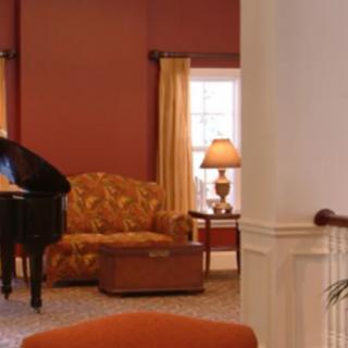 A cozy living room with a grand piano, sofa, and warm lighting.