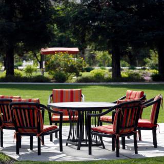 A set of outdoor patio furniture with a table and chairs in a garden setting.