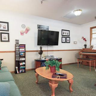 A cozy living room featuring a television, piano, and various decorations.