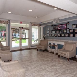 A cozy lobby with comfortable seating and framed pictures on the wall, featuring large windows that let in natural light.