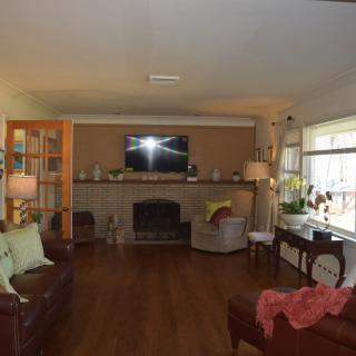 A cozy living room with a fireplace, sofa, and television, featuring hardwood floors and stylish decor.
