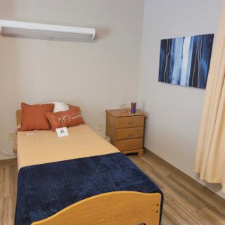 A cozy and minimalist bedroom setup featuring a single bed, wooden nightstand, and decorative elements.
