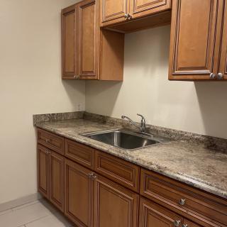 A kitchen featuring wooden cabinets and a marble countertop with a double sink.