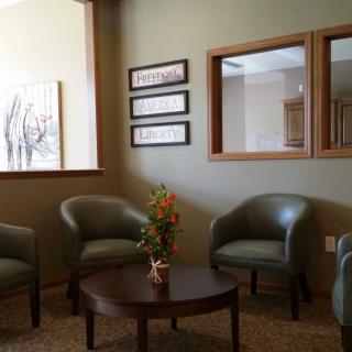 A cozy waiting room with chairs and a table, featuring decorative elements.
