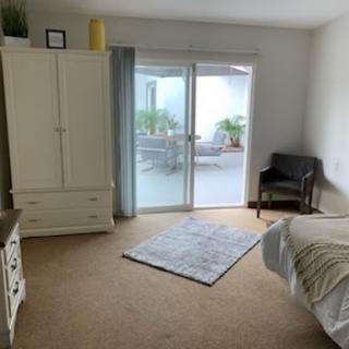 A cozy bedroom with a wardrobe, armchair, and sliding doors leading to a patio.
