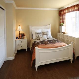 A cozy bedroom with classic white furniture and a warm, inviting atmosphere.