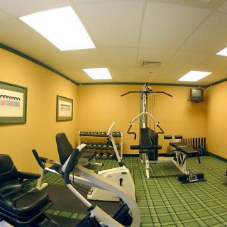A compact gym room equipped with various exercise machines and weights.