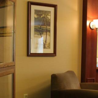 A cozy corner featuring a framed artwork on the wall, a comfortable chair, and warm lighting.