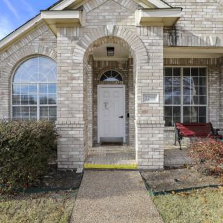 Front entrance of a brick house with an archway and large windows.