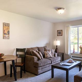 A cozy living room with a sofa, coffee table, and lamp near a window.