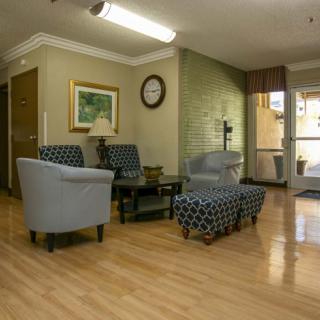 A cozy lobby area with comfortable chairs, a coffee table, and decor elements like a painting and a clock on the wall.