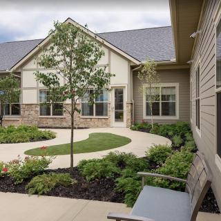 A serene courtyard with landscaped greenery and a pathway leading to a residential building.