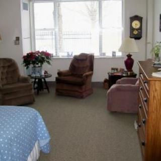 A cozy living room with armchairs and a clock on the wall.