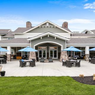A stylish restaurant building with outdoor seating and blue umbrellas under a clear blue sky.