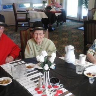 A group of elderly individuals enjoying a meal together, wearing hats and smiling at the table.