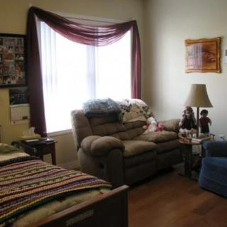 Cozy living room with a window, couches, and a lamp.