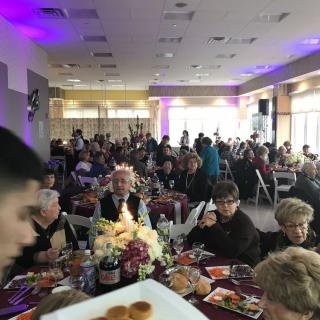 A large group of people enjoying a banquet in a decorated indoor venue.