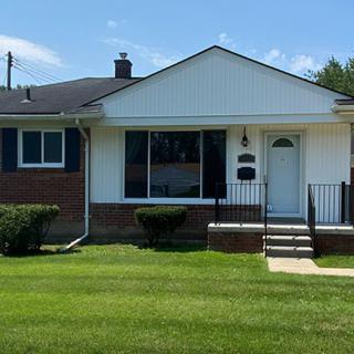 A single-story suburban house with a brick facade and a well-maintained lawn.