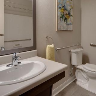 A modern bathroom with a sink, mirror, toilet, and decorative artwork.