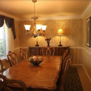 A well-decorated dining room featuring a wooden table with matching chairs, a chandelier, and elegant curtains.