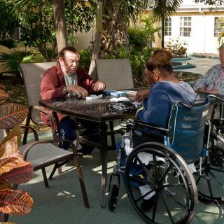 A group of people sitting around a table outdoors, engaging in conversation.