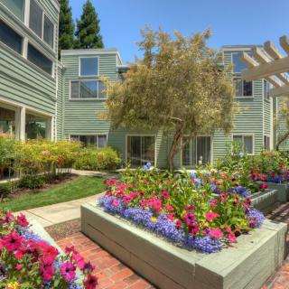 A beautifully landscaped garden with vibrant flowers in front of an apartment building.