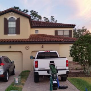 A white pickup truck parked in the driveway of a two-story house during sunset.