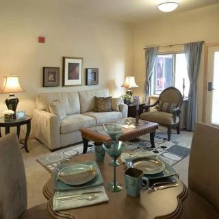 A cozy living and dining area with neutral tones, featuring a comfortable sofa, decorative cushions, and a well-set dining table.