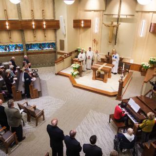 A church service in progress with a congregation gathered and priests at the altar.