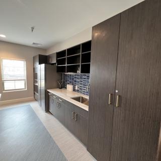 A modern kitchen with dark cabinets and open shelving, featuring a sleek design and ample storage.